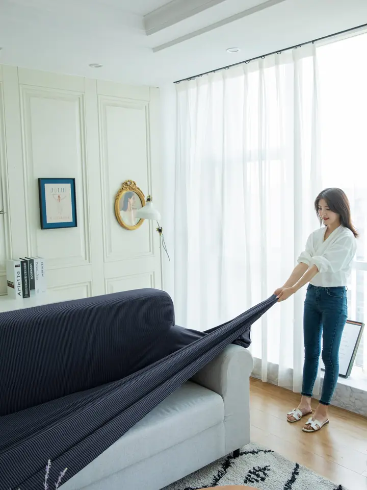 Navy stretch slipcover being fitted over a sofa